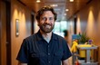 © starush - A smiling man with a beard stands in a modern indoor setting with warm lighting and wooden accents