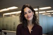 © Rifqi - Confident young professional woman smiling in a modern office setting portrait headshot of a friendly businesswoman in a contemporary workspace featuring glass walls and warm