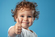 © Babb - A baby with curly hair is smiling and giving a thumbs up