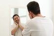 © New Africa - Handsome man looking at himself in mirror indoors