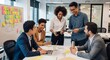 © creativestock - Diverse group collaborating around a table with a laptop and sticky notes in a modern office