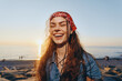© SHOTPRIME STUDIO - Lifestyle woman in modern boho-western denim street style smiling on sunny beach with warm film color glow and a red bandana in her hair during golden hour.