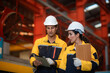 © pornchai - Latino male industrial engineer and female auditor working team wearing safety uniform workwear Walking to Audit, discussing and checking safety of working area and warehouse in an industrial factory.