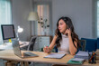 © Apichat - woman is sitting at a desk with a laptop and a cell phone