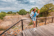 © EdNurg - Female tourist using smartphone walking down wooden stairs at the ruins of Troy, a world heritage site in Turkey