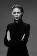 © SHOTPRIME STUDIO - black and white portrait of serious woman in black suit with crossed arms against plain background with confident expression and slicked-back hair, studio lighting