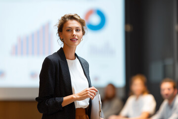 Poster - A woman stands in front of a large screen with a presentation