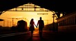 © goslim - Silhouette of a Couple Holding Hands Walking at a Train Station at Sunset