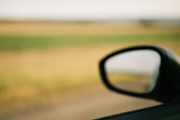 Aufkleber - Blurry landscape seen through a moving vehicle's window with soft focus and rearview mirror reflection