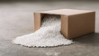 © SnowElf - A cardboard box is open with white foam pellets spilling out onto the concrete floor. Packaging, storage, waste, loose fill, transportation