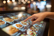 © Daniel - Close-up of a finger pointing at a touch screen display with food options, showcasing the modern self-service ordering system in a fast food restaurant environment.