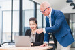 © PRIME STOCK LAB - Businesswoman and senior businessman working together office desk, discussing project laptop with teamwork and mentoring, modern workplace environment, professional collaboration, positive mood