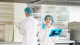 厨房をチェックする衛生白衣を着た男女作業員