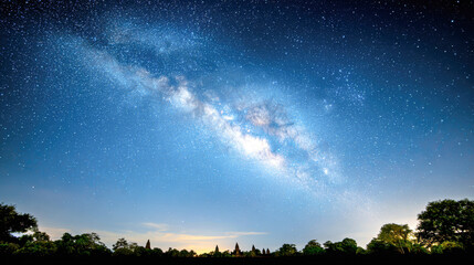 a stunning night sky showcases the milky way galaxy stretching over a silhouetted tree line on a cle