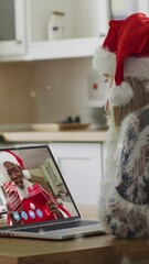 Poster - Animation of snow falling over happy caucasian woman in santa hat on laptop video call