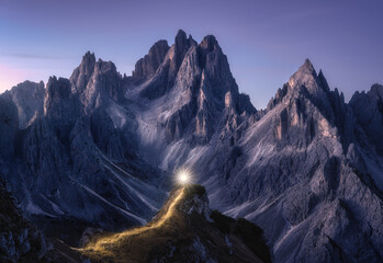 Wall Mural - Flashlight trails on mountain path against high rocks at night in autumn. Tre cime, Dolomites, Italy. Colorful landscape with light trails, illuminated path on the hill, mountain peaks, sky with stars