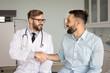 © fizkes - Cheerful young Latin patient shaking hands with male physician, thanking for medical help, support, consultation, successful therapy, smiling, laughing. Doctor giving handshake to man in exam room