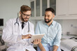 © fizkes - Positive male doctor and patient discussing medical examination electronic results. Practitioner thumbing through medical records on tablet pc, using gadget, giving consultation