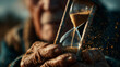 © Dzmitry - Elderly hands gently hold a time frozen hourglass amidst golden sand reflections