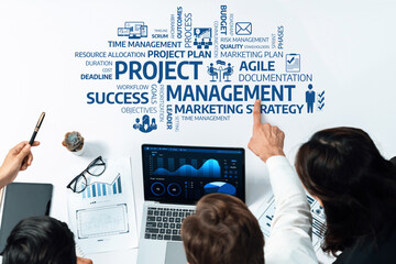 Poster - This stock photo captures a collaborative project management session, featuring a diverse group engaged in strategic planning, with charts and a laptop illustrating success metrics. Amity
