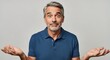 © Richafuji - Portrait of a middle-aged person with graying hair expressing uncertainty against a neutral gray background. He wears a blue shirt with an open-mouthed expression and raised eyebrows.