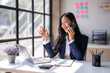 © Wasana - A woman is talking on her cell phone while sitting at a desk