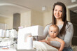 © Михаил Решетников - A young woman sews in the kitchen and holds a small child. Mom teaches her little son to sew on a sewing machine. Self-isolation homework