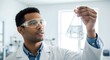 © yazidkautsar1 - A scientist in a lab coat examines a flask of liquid with focused attention.