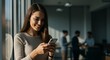 © Sookiee - Smiling Woman Using Smartphone in Modern Office Setting
