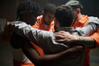 © pressmaster - Group of young multiethnic men standing in close circle embracing each other during group therapy session in prison setting showing support and unity