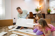 © Jelena - Family bonding while assembling furniture together in the living room