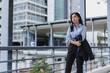 © Phimwilai - Businesswoman holding jacket looking away on modern city footbridge