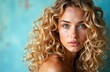 © starush - Close-up of a young woman with curly blonde hair and blue eyes against a vibrant blue background