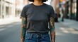 © Meow Creations - Woman in plain grey t shirt with full sleeve tattoos standing on city street