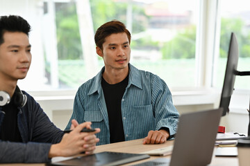 two young creative professionals discussing ideas in a bright modern office, brainstorming around la