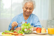 © amazing studio - Asian elderly woman patient eating salmon steak breakfast with vegetable healthy food in hospital.