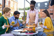 © sofiko14 - A friendly waitress serves pizza to a group of friends at an outdoor restaurant, enjoying drinks.