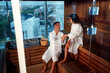 © Zoran Zeremski - Middle-aged couple in bathrobe enjoying wellness and heat therapy in wooden sauna.
