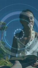 Poster - Animation of statistics and graphs over woman sitting on grass reading book in park