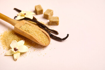 Wall Mural - Wooden scoop of vanilla sugar with pods and flowers on light background, closeup