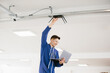 © dsheremeta - Technician installing wireless router on ceiling using laptop