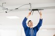 © dsheremeta - Technician installing wireless router on ceiling in office building