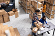 © DC Studio - Local brand supply room staff work at distribution hub for order processing and hand packing merchandise. Ensuring local shipping and in house logistics operations for retail fulfillment.