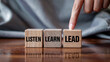 © Design Stock - Finger pointing to wooden blocks with the words listen learn lead symbolizing personal development and career progression