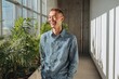 © Zaheer - Casual male startup cofounder laughing in hallway with plants side sunlight streaming window golden palette with soft lens