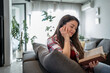 © Migma_Agency - Young woman relaxing on sofa reading a book at home