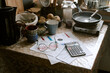 © AnnaStills - Kitchen table holding overdue bills marked pass due, calculator, eyeglasses, mugs, bread and frying pan, illustrating financial hardship and daily struggle for poor elderly couple