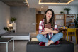 © Migma_Agency - Young woman relaxing on sofa holding a book in modern apartment