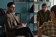 © Mediaphotos - Man holding notebook leading therapy session with man and woman listening attentively in office setting