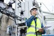© Sumala - Engineer is working at high voltage power substation performing inspection and check of infrastructure using radio and clipboard to ensure safety and functionality